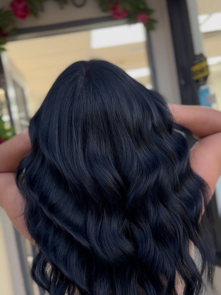 Long jet black hair with extensions, styled in deep glossy waves