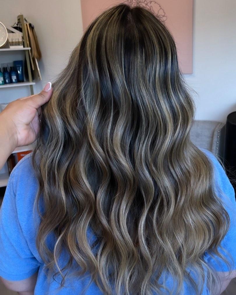 Long dark brunette hair with extensions, styled in glossy waves